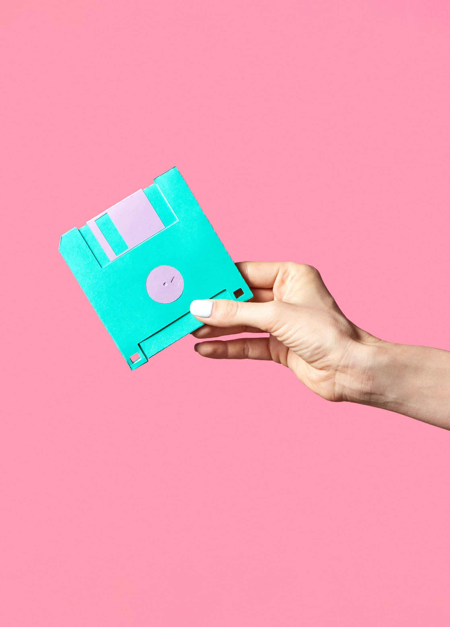 Isolated hand holding a floppy disk in front of a bright background