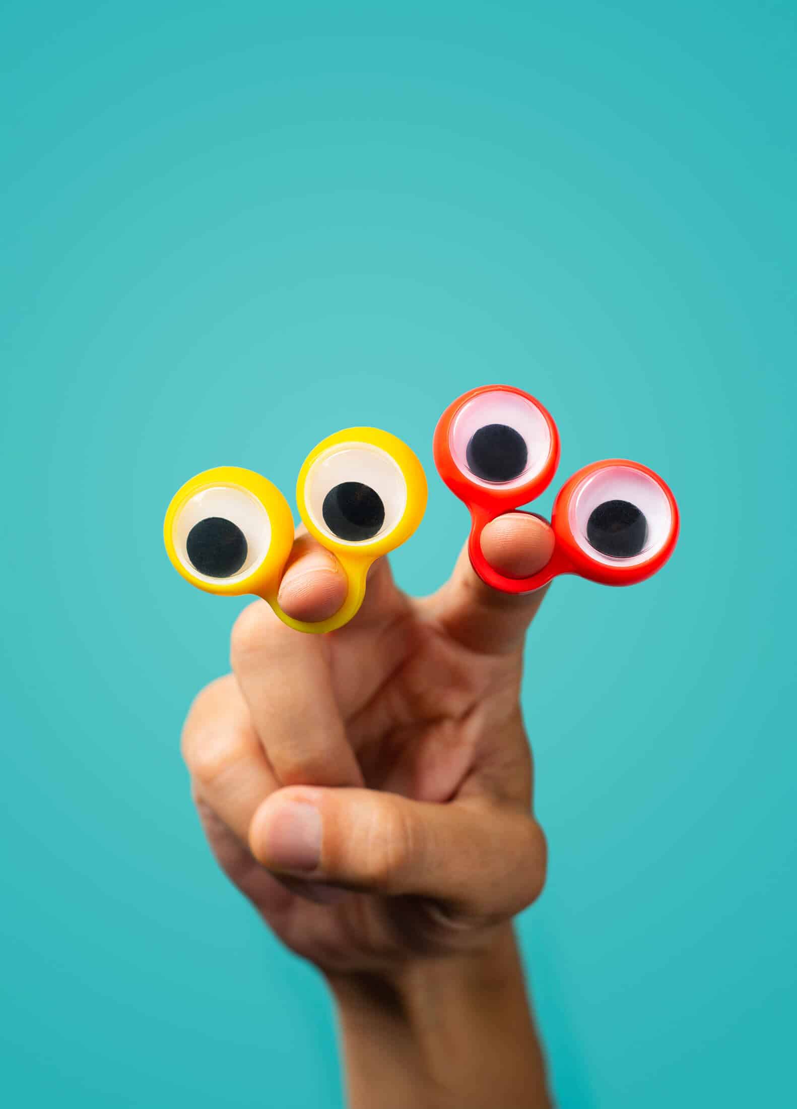 Isolated hand with toy googly eyes on front of a bright background